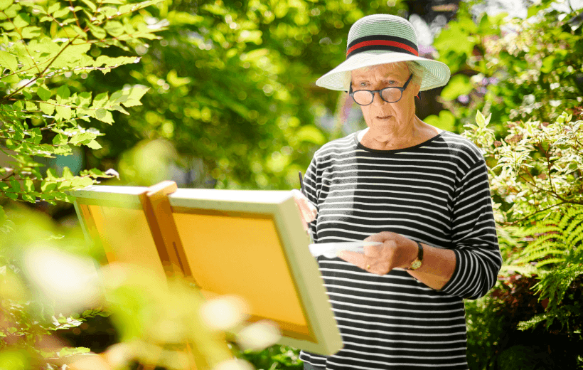 woman painting on canvas out in nature
