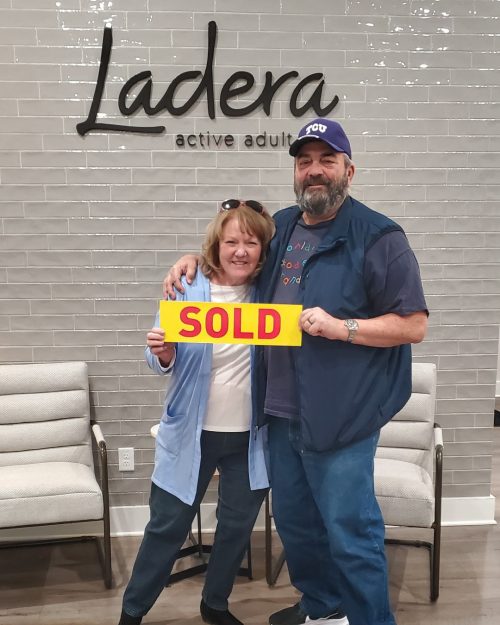 couple holding "SOLD" sign