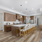 Spacious Ladera Living kitchen with wood cabinetry, large island, pendant lighting, and seating for six at the breakfast bar