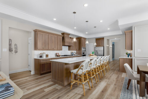 Spacious Ladera Living kitchen with wood cabinetry, large island, pendant lighting, and seating for six at the breakfast bar