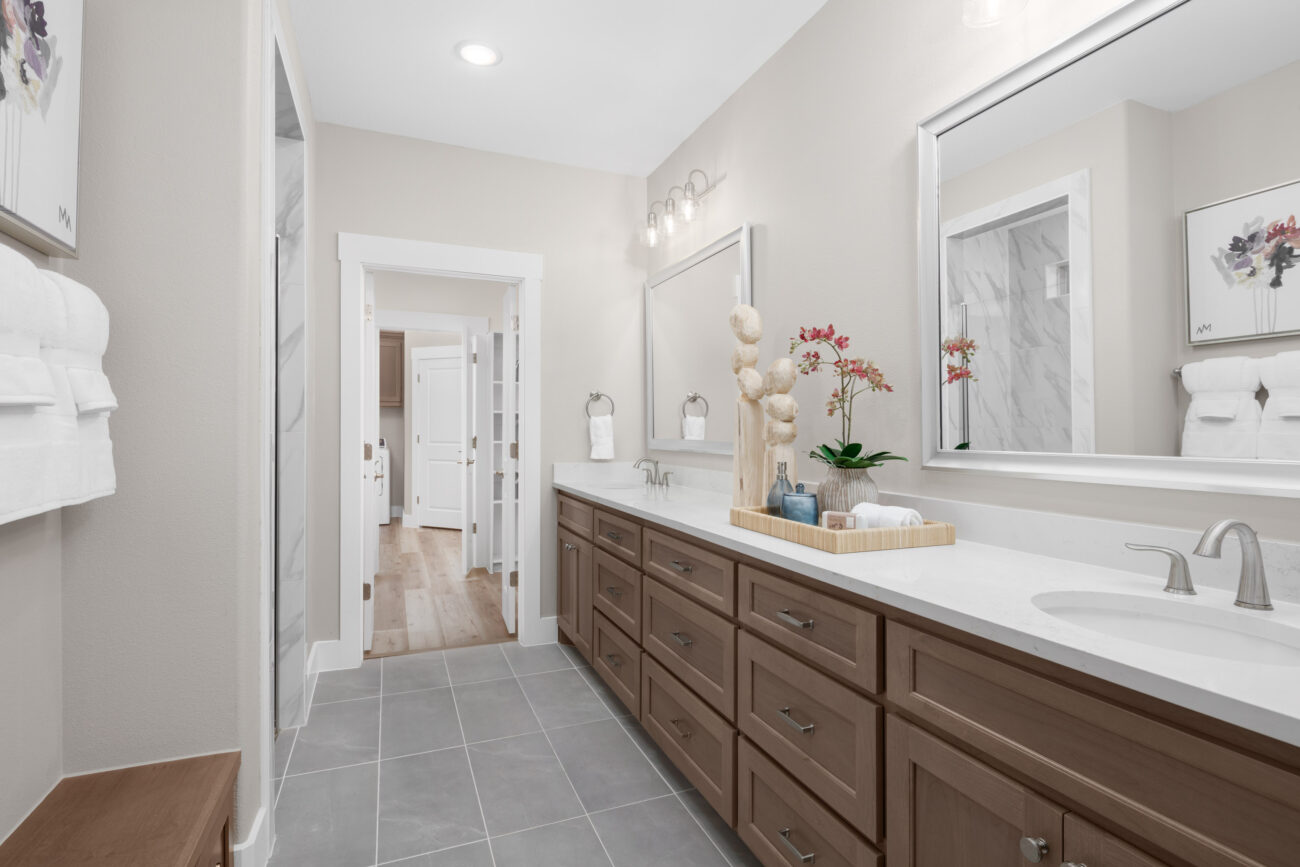 Modern bathroom at Ladera Living featuring dual sinks, natural wood cabinetry, and sleek decor with neutral tile and finishes