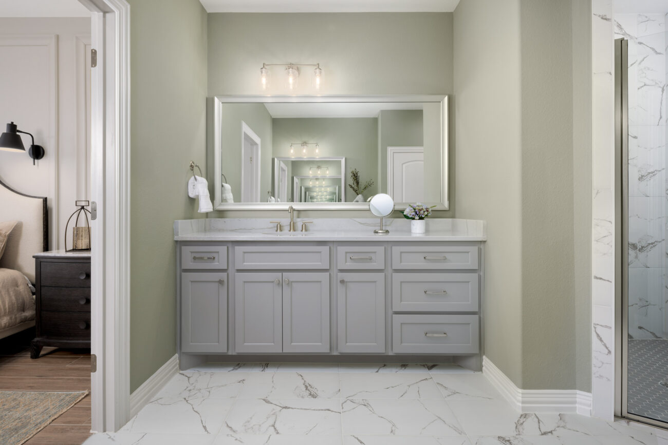 Ladera Living bathroom vanity with wide mirror, modern lighting, and marble-look tile floor, next to a walk-in shower