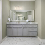 Ladera Living bathroom vanity with wide mirror, modern lighting, and marble-look tile floor, next to a walk-in shower