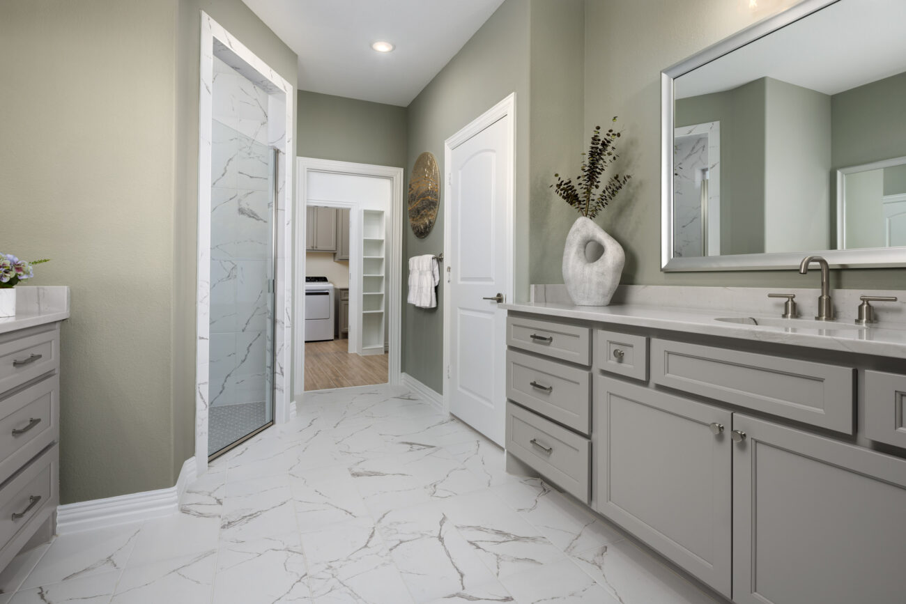 Elegant bathroom with double vanity, large mirror, and marble-look tile flooring in a Ladera Living home