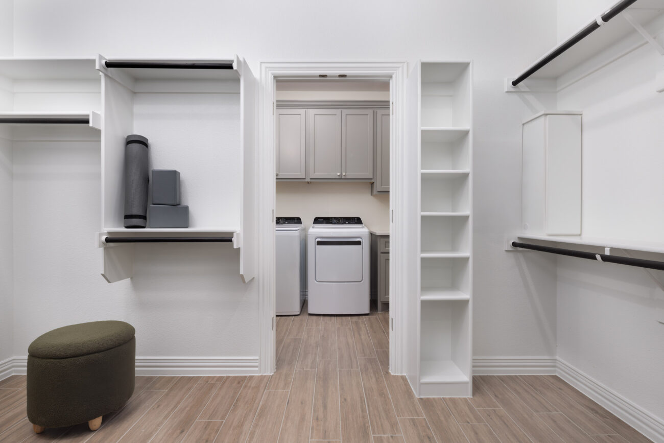 Spacious walk-in closet with built-in shelving and access to a laundry room with washer and dryer at Ladera Living