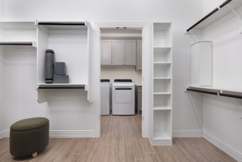 Spacious walk-in closet with built-in shelving and access to a laundry room with washer and dryer at Ladera Living