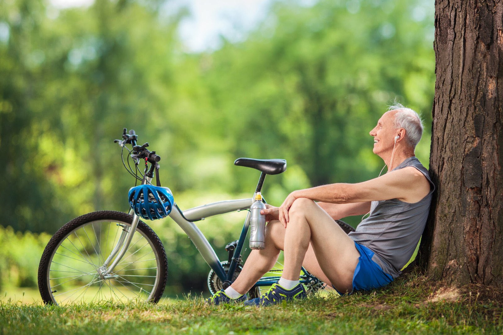 an-elderly-biker-sitting-under-the-tree-while-listening-to-a-music