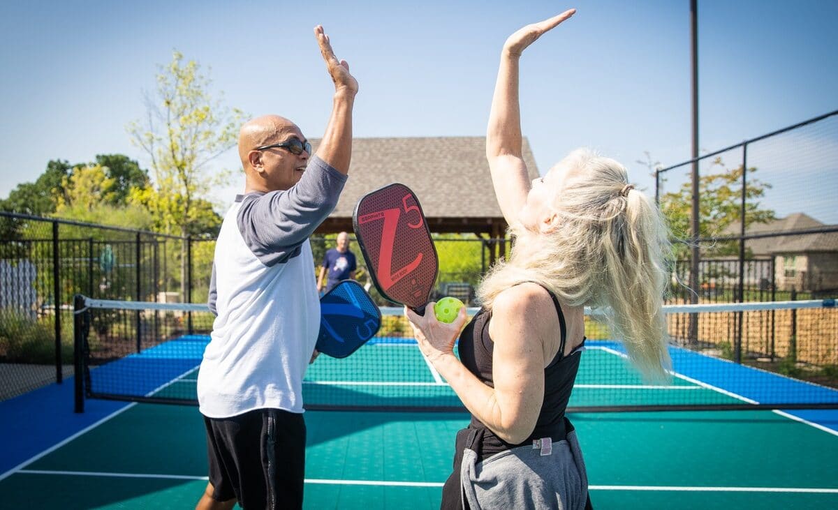 man and women high fiving on tennis court
