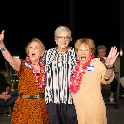 three women waving at an event