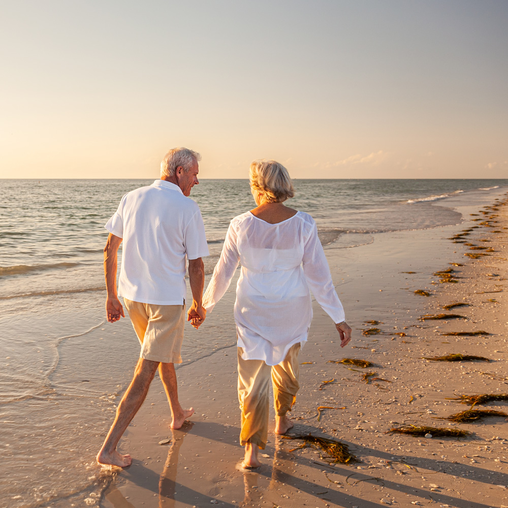 couple holding hands walking on beach