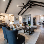 Spacious open-concept living area with vaulted ceiling, dark beams, modern kitchen, and home office space
