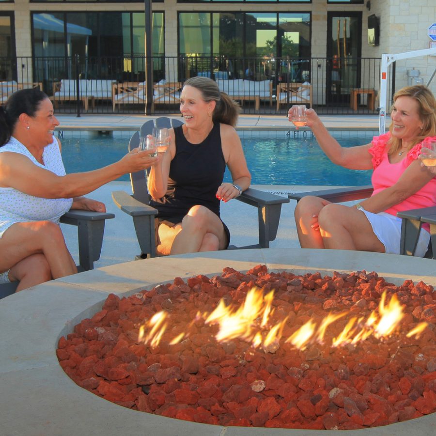 women sitting around firepit toasting wine