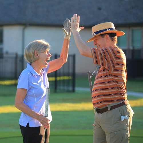 woman and man high-fiving on putting green