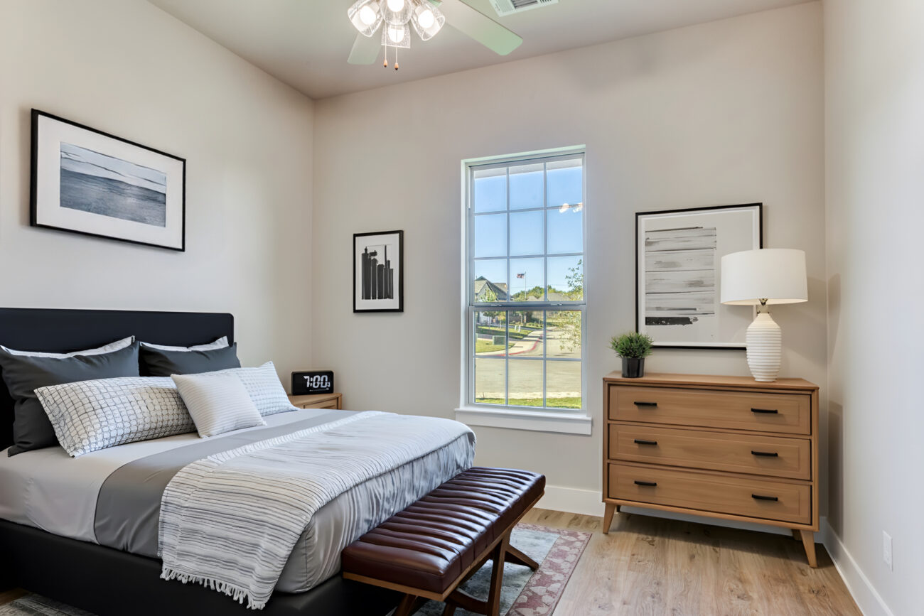 Bright bedroom with modern bed, dresser, ceiling fan, and natural light in a Ladera Living home