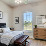 Bright bedroom with modern bed, dresser, ceiling fan, and natural light in a Ladera Living home