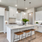 Modern white kitchen with island seating, pendant lighting, and quartz countertops in a Ladera Living home