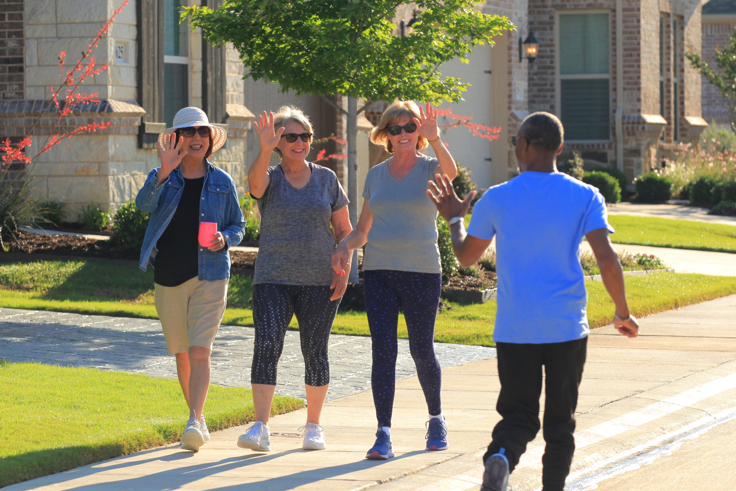 Ladera at Timberbrook lifestyle - group of three women waving at a man while on a walk.