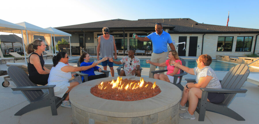 Group of active adults toasting around the fire pit in a Ladera Living Dallas 55+ Community