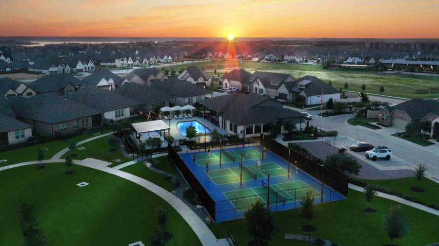 Aerial image showing The HUB Amenity Center in a Ladera Living 55+ community. The amenity campus includes pickleball courts, a pool, and a clubhouse, with homes surrounding it.